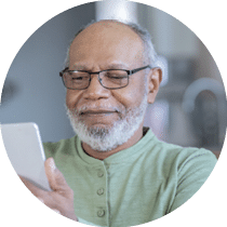 Senior male wearing eyeglasses uses mobile phone in domestic kitchen